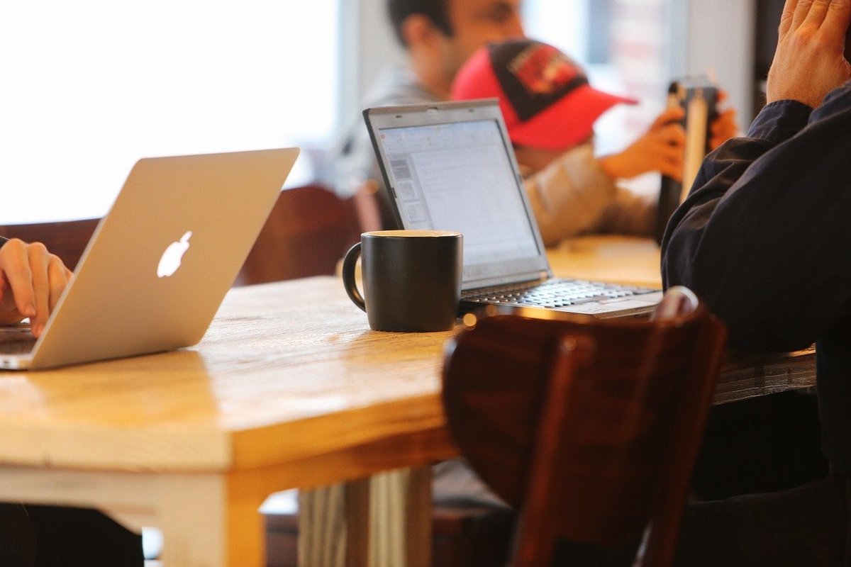 Modern workspace with laptops, coffee, and casual collaboration.