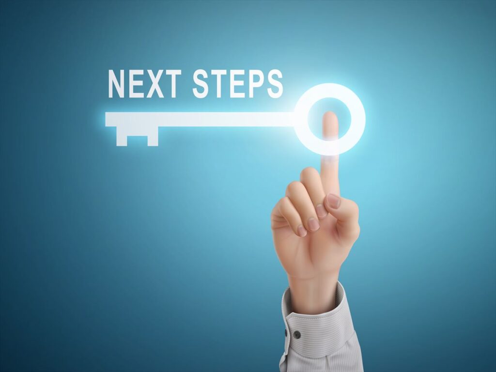 青いグラデーションの背景に、指で「NEXT STEPS(ネクスト ステップス)」と書かれた光る鍵に触れている様子。次のステップへの鍵や解決策を象徴している。