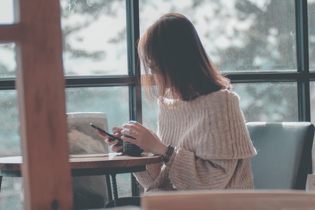 喫茶店でスマフォを操作する女性