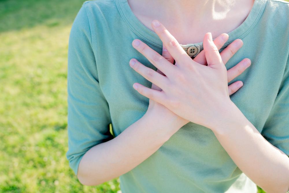 両手を胸に当てて気持ちを確かめる女性、感謝や決意を象徴するイメージ
