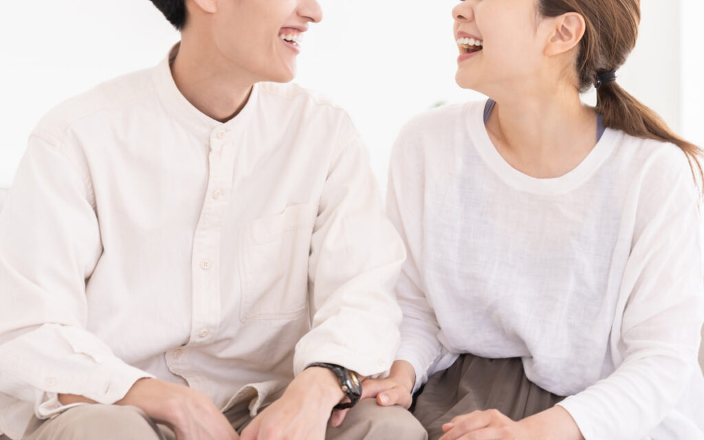 自然な笑顔で向き合う男女のカップル。信頼と安心感を感じさせる成婚イメージ