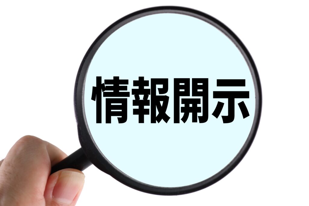 虫眼鏡で「情報開示」という文字を拡大している画像
