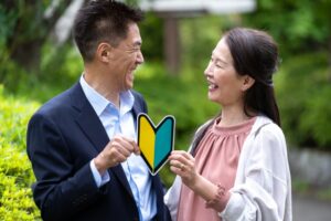 初心者マークを一緒に持ちながら笑い合う中高年カップル、婚活の新しい一歩を象徴する写真